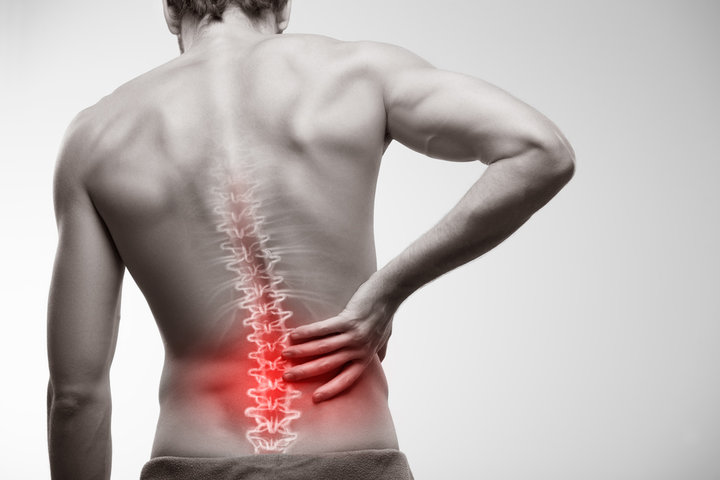 Person holding lower back in pain due to degenerative disc disease